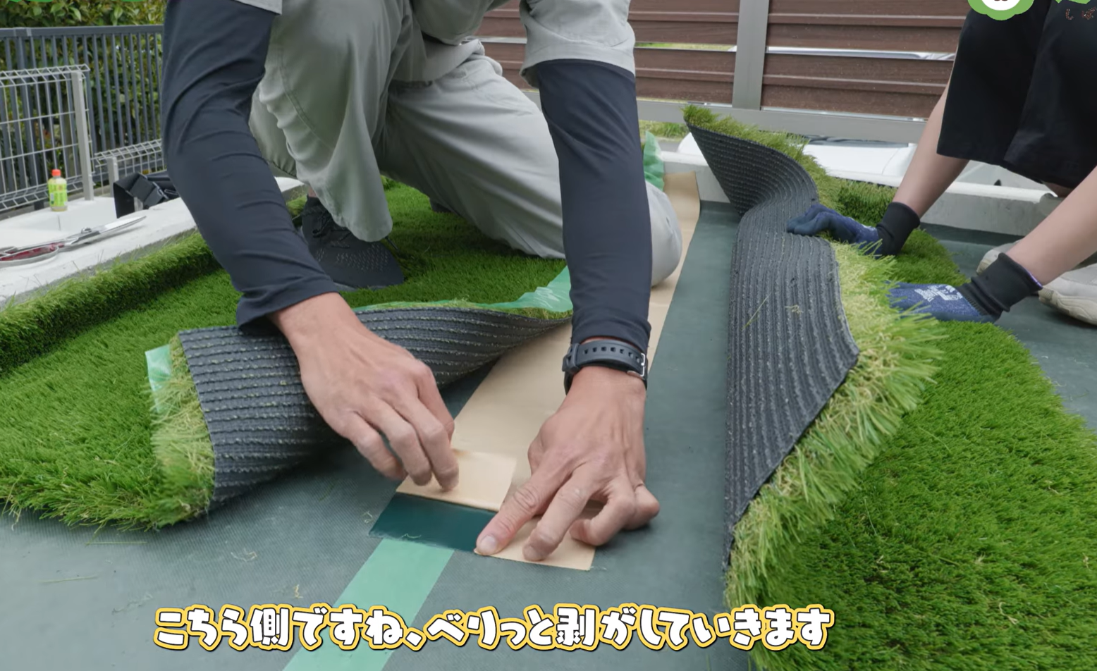 ジョイントテープの剥離紙を剥がして人工芝に貼っている様子